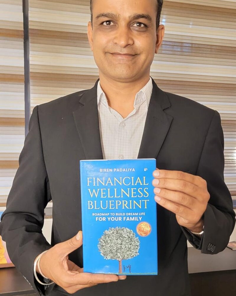 Biren Padaliya, published author of Financial Wellness Blueprint, holding his paperback